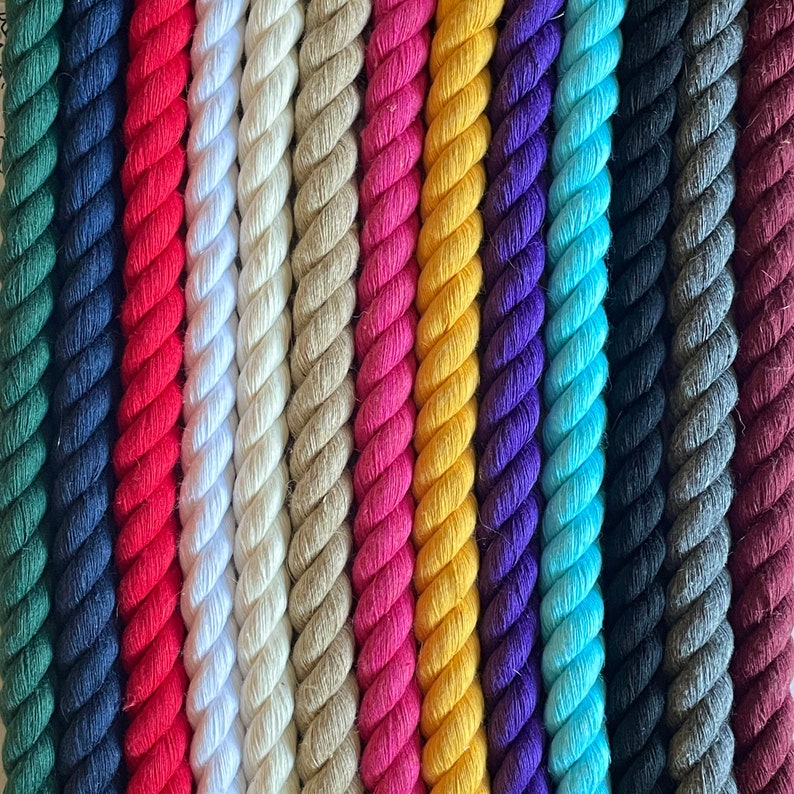 May include: A close-up of a variety of colourful twisted ropes. The ropes are arranged vertically, showcasing a spectrum of colours including red, white, tan, pink, yellow, purple, blue, black, grey, and burgundy. The texture of the rope is clearly visible.