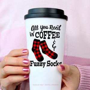 May include: White travel mug with a black lid and a black graphic that says "All you need is coffee & fuzzy socks". The graphic also includes a pair of red and black plaid socks.