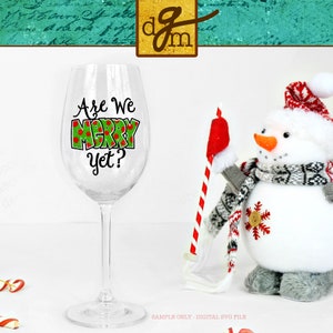 May include: A clear wine glass with a green and red design that says "Are We Merry Yet?"  A snowman with a red hat and a scarf is holding a red and white striped candy cane.
