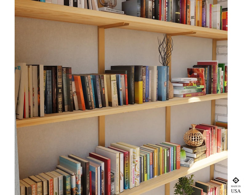 Floating bookcase with brass shelf brackets and solid wood shelves.