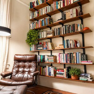 A home library featuring large wall-mounted bookshelves made from solid hardwood and solid steel brackets filled with books of various sizes and colors.