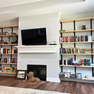 Heavy duty wall mounted floating bookcase featuring solid ash book shelves and black industrial American steel brackets. All handmade in the USA.