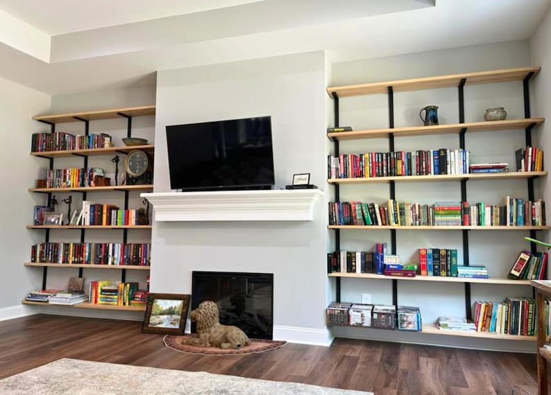Heavy duty wall mounted floating bookcase featuring solid ash book shelves and black industrial American steel brackets. All handmade in the USA.