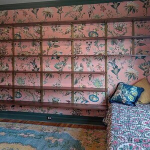 Wall mounted bookcase in a whimsical room featuring black walnut solid hardwood shelves and heavy duty brass finish steel brackets.