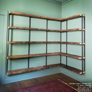 Large corner bookshelf on green wall. Shelvea are Reclaimed wood and steel metal modular shelf brackets