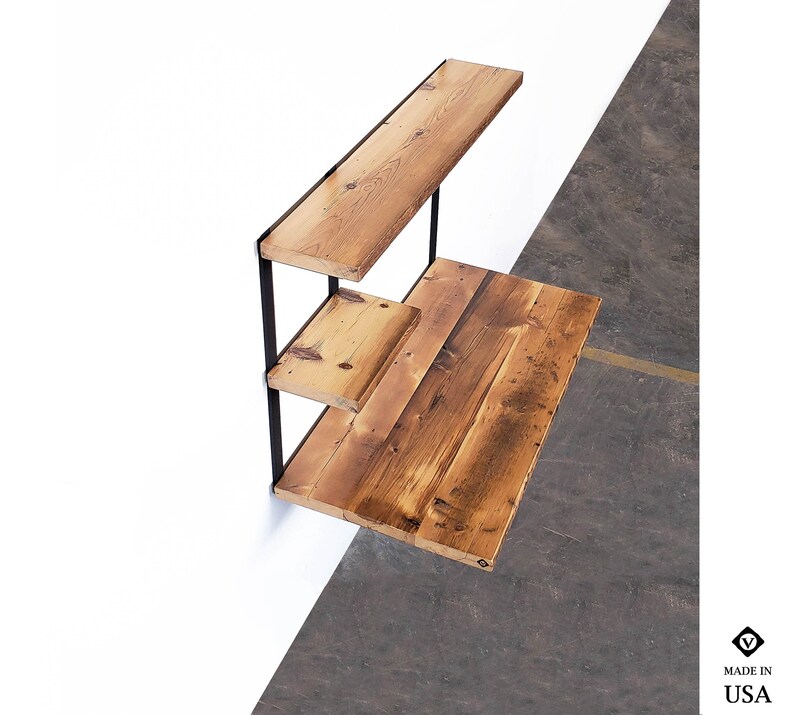 Puede incluir: Un escritorio de pared con tres estantes hechos de madera recuperada y soportes de metal negro. El escritorio est&aacute; plegado y los estantes est&aacute;n vac&iacute;os.