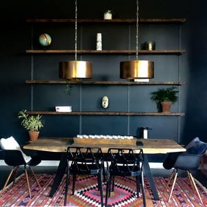 Moody dining room with clean lines featuring heavy duty bookshelves offering sleek storage and display for art. Solid reclaimed pine hardwood supported by black american steel brackets.