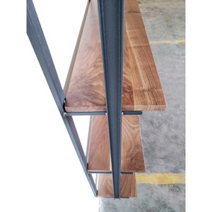 Detail photo of Heavy duty steel shelf brackets on tall wall mounted bookshelf. Floating bookase with black walnut shelves