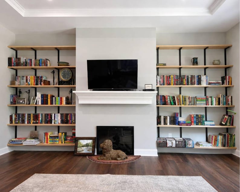 Tall wall mounted bookshelves on both sides of a fireplace. Solid ash wood shelves with black brackets.