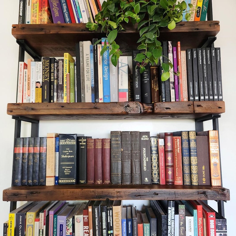 detailed image of thick reclaimed pine bookshelves with matte black steel shelf brackets. Books on shelf with plant