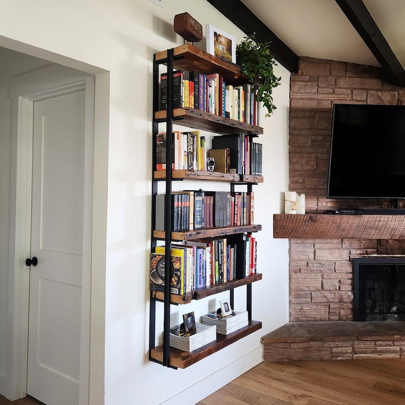 reclaimed wood bookshelf with black metal brackets on white wall next to fireplace