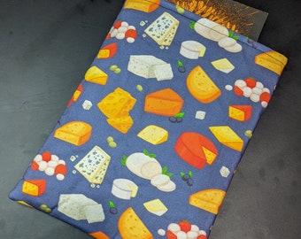 May include: A blue fabric sleeve with a cheese pattern. The pattern includes various cheese types in yellow, orange, white, and blue, along with olives and red and white balls. A book or notepad is partially visible inside the sleeve.