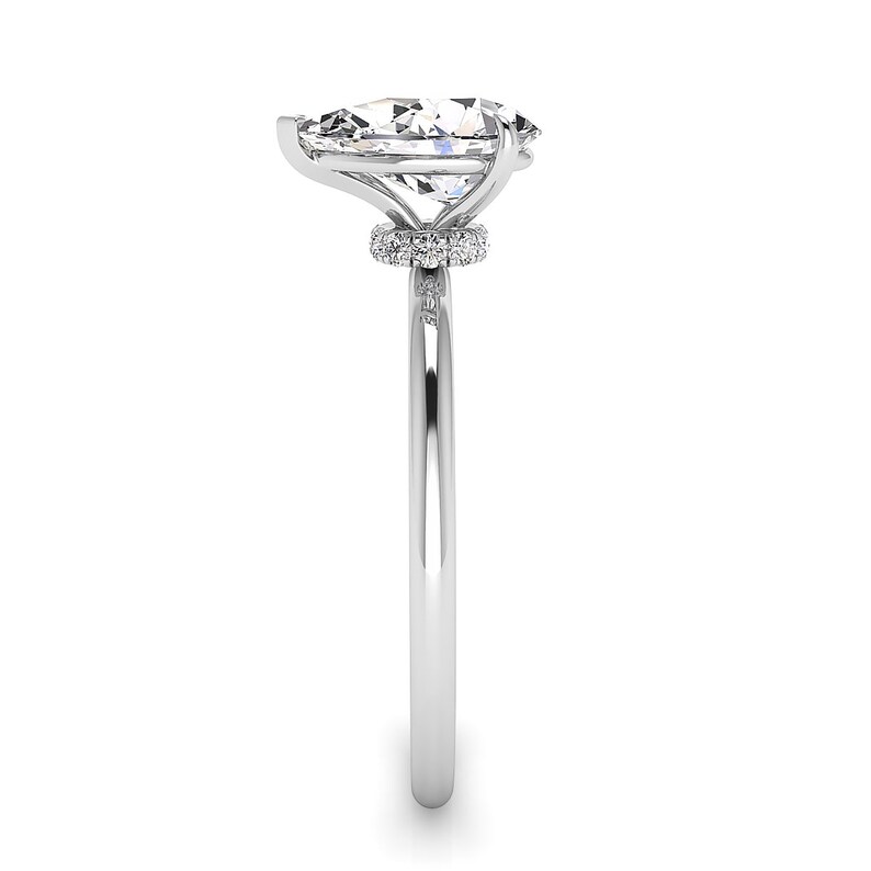 Puede incluir: Un anillo de plata con un gran diamante de forma ovalada engastado en un halo de diamantes m&aacute;s peque&ntilde;os. El anillo tiene una banda simple.
