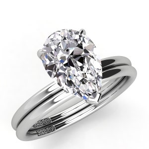 Puede incluir: Un anillo de compromiso de diamante de forma pera con una banda de boda a juego. Ambas bandas son de oro blanco y llevan la inscripci&oacute;n "SABEHI" en el interior.
