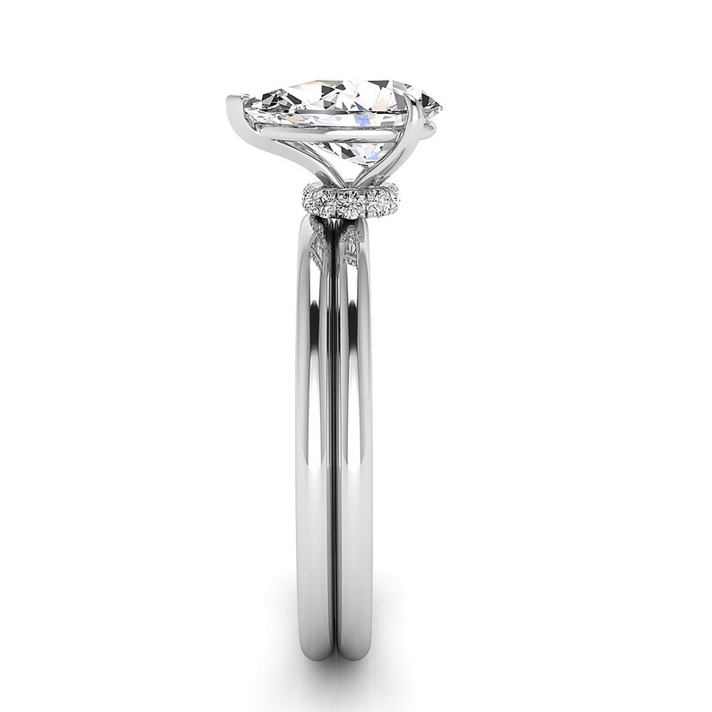 Puede incluir: Un anillo de compromiso de plata con un gran diamante de forma ovalada y un halo de diamantes m&aacute;s peque&ntilde;os. El anillo est&aacute; montado en una banda delgada con una banda de boda a juego.