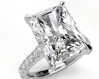 May include: A silver engagement ring with a large, rectangular, clear diamond. The diamond is set in a prong setting and the band is accented with smaller diamonds.