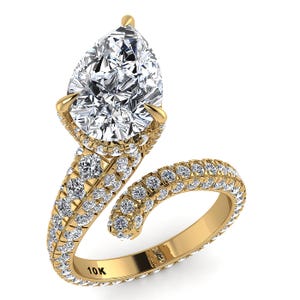 Può includere: Un anello bypass in oro giallo 10K con una grande pietra centrale a goccia e una fascia con incastonatura a pavé coperta da numerosi piccoli diamanti bianchi rotondi. L'anello ha un design aperto a spirale con la scritta 10K incisa all'interno.