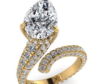 Puede incluir: Un anillo bypass de oro amarillo de 10K con una gran piedra central en forma de pera y una banda con engaste pavé cubierta de numerosos diamantes blancos redondos pequeños. El anillo tiene un diseño abierto en espiral con el texto 10K grabado.
