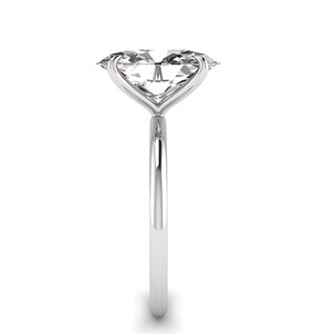 May include: A solitaire engagement ring with a large, clear, oval-cut diamond. The diamond is set in a delicate, polished silver band. The ring is shown against a white background, highlighting its elegant design.