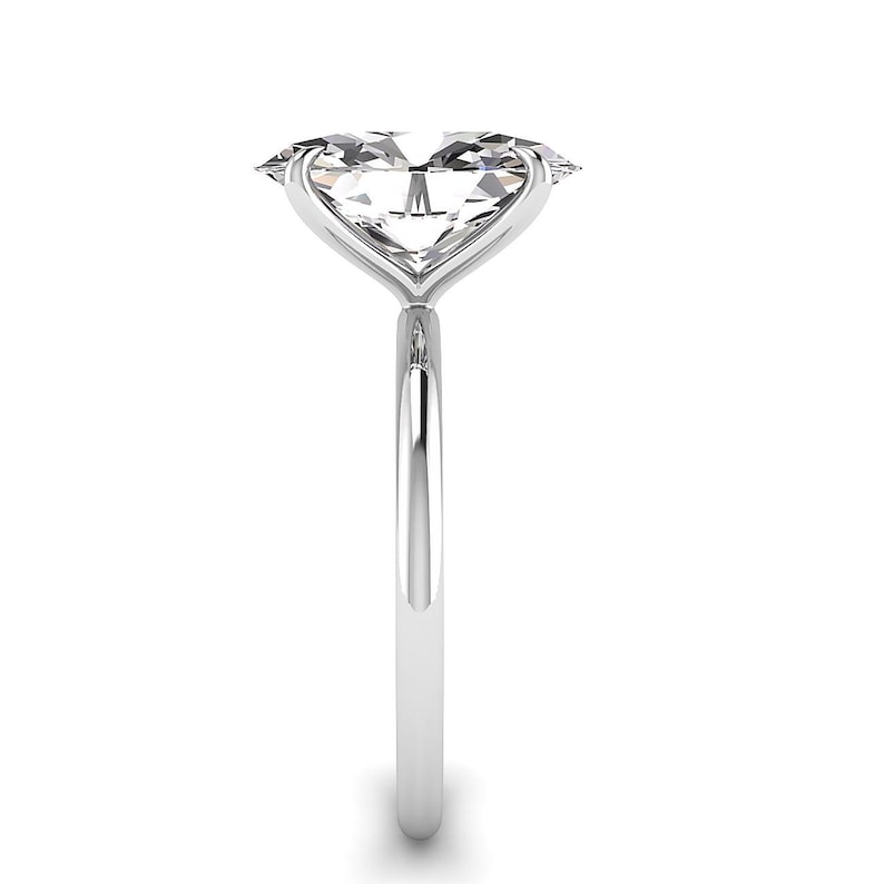 May include: A solitaire engagement ring with a large, clear, oval-cut diamond. The diamond is set in a delicate, polished silver band. The ring is shown against a white background, highlighting its elegant design.