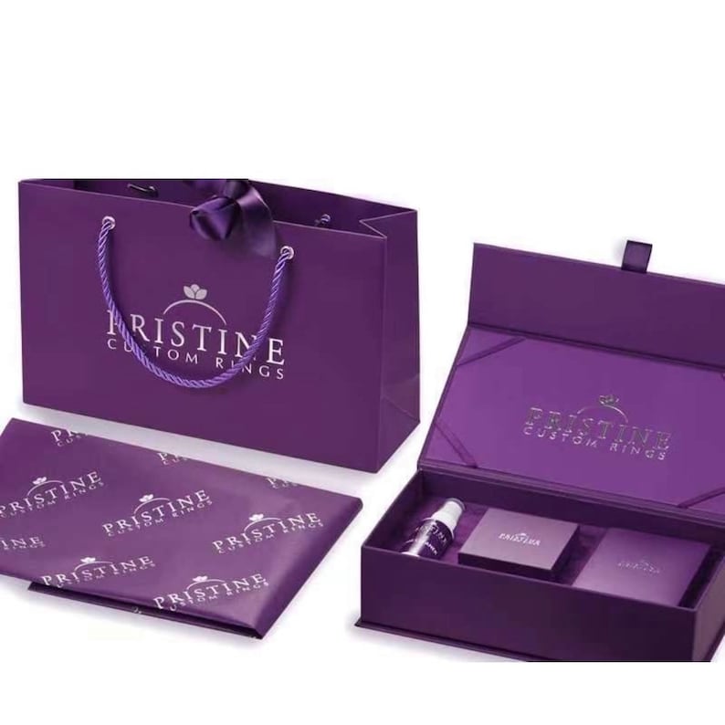 May include: A purple gift set featuring a shopping bag, tissue paper, and a presentation box. The bag has a rope handle and a satin ribbon. The box contains small items, and all items display the "PRISTINE CUSTOM RINGS" logo in white.
