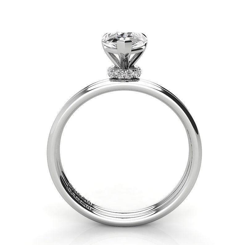 Puede incluir: Un anillo de compromiso de plata con un diamante redondo y un halo de diamantes m&aacute;s peque&ntilde;os.