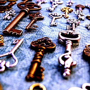 May include: A collection of antique keys in various styles and finishes, including silver, gold, and brass. Some keys have intricate designs and ornate details.