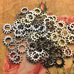 May include: A large pile of silver metal gears with a floral background. The gears are all the same size and have a smooth, shiny finish.
