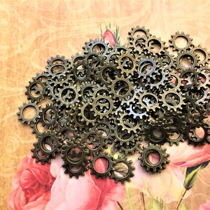 May include: A large pile of antique gold-toned metal gears. The gears are all the same size and have a slightly distressed finish.