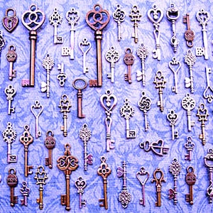 May include: A collection of antique-style keys in various shapes and sizes, with intricate designs and a silver finish. The keys are arranged on a blue background.