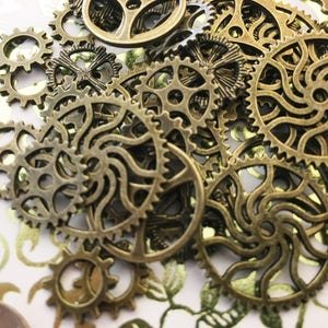 May include: A collection of antique gold-toned metal gears of various sizes and shapes. The gears are arranged in a random pattern, creating a visually interesting and intricate design.