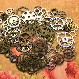 May include: A collection of antique-style metal gears in various sizes and shapes. The gears are in shades of gold, silver, and bronze, and have intricate designs.