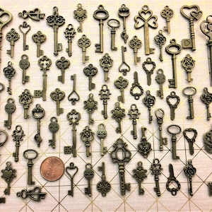 May include: A collection of 50 antique-style skeleton keys in various shapes and sizes. The keys are made of metal and have a bronze finish. They are arranged in a grid pattern on a pink background.