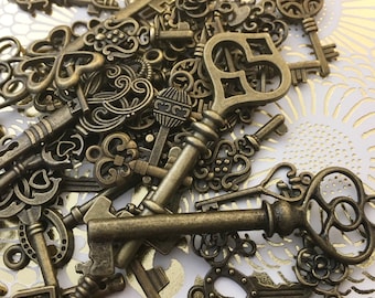 Op de afbeelding: Een verzameling antieke skeletsleutels in verschillende vormen en maten, met ingewikkelde ontwerpen en sierlijke details. De sleutels zijn gemaakt van bronskleurig metaal en zijn verspreid over een witte achtergrond met een bloemenpatroon.