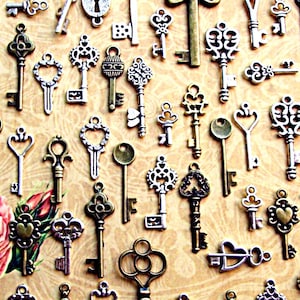 May include: A collection of antique-style keys in various shapes and sizes, with intricate designs and a mix of silver and gold tones. The keys are arranged on a textured background.