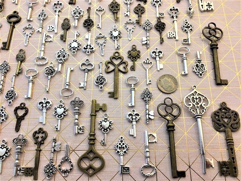 May include: A collection of antique-style skeleton keys in silver and bronze finishes. The keys are arranged on a pink background with a geometric pattern.