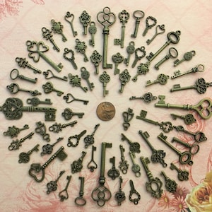 May include: A collection of antique-style skeleton keys in various shapes and sizes, arranged in a circular pattern on a pink and white patterned surface. The keys are made of metal and have a bronze finish.