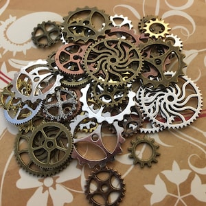 May include: A collection of assorted metal gears in silver, gold, and copper tones. The gears are of various sizes and shapes, with intricate designs.