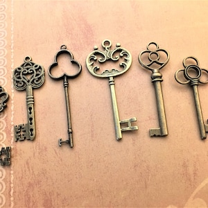 May include: Six antique-style keys in various designs and sizes, arranged on a light brown surface. The keys are made of a bronze-colored metal, with ornate details and keyholes. The keys are decorative and suitable for crafts or vintage-themed projects.