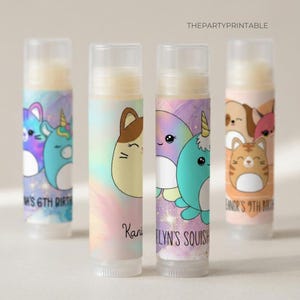 May include: Four lip balm tubes with colorful designs. Each tube features a different cartoon animal, including a cat, dog, and narwhal. The tubes have text that reads "M's 6th Birth", "Kani", "Elyn's Squish", and "Eanor's 9th Birth".