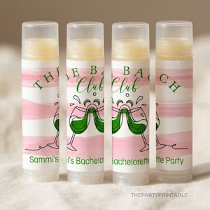 May include: Four lip balm tubes with clear caps. Each tube has a pink and white striped design with green text that reads "THE BACHELORETTE CLUB". The tubes also feature a graphic of two wine glasses clinking. The text "Sammi's Bachelorette Party" is also visible.