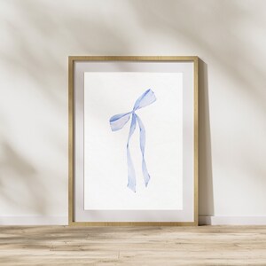 Op de afbeelding: Een ingelijst aquarel schilderij van een blauw lint gebonden in een strik.