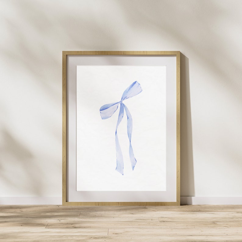 Op de afbeelding: Een ingelijst aquarel schilderij van een blauw lint gebonden in een strik.