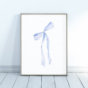 Op de afbeelding: Een ingelijst aquarel schilderij van een lichtblauwe strik op een witte achtergrond.