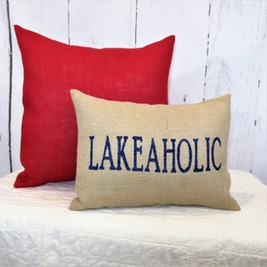 May include: Two decorative pillows, one red and one beige with the text "LAKEAHOLIC" in blue embroidery.