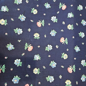 May include: A dark blue fabric with a repeating pattern of small, colorful flowers. The flowers are in shades of pink, yellow, and blue.
