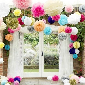 May include: A variety of colorful tissue paper pom-poms and honeycomb balls are hung from the ceiling, creating a festive and whimsical atmosphere. The decorations are arranged in a cascading pattern, with the largest pom-poms at the top and the smaller honeycomb balls at the bottom.