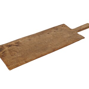 May include: A rustic, rectangular wooden cutting board with a handle. The board is a warm brown color, showing the natural wood grain. The handle is a smaller, rectangular extension of the board.