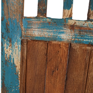 May include: Close-up of a wooden door with a blue paint finish. The paint is peeling and chipped, revealing the natural wood underneath. The door is made of vertical planks.