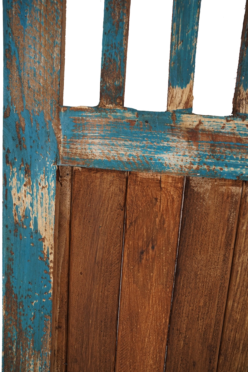 May include: Close-up of a wooden door with a blue paint finish. The paint is peeling and chipped, revealing the natural wood underneath. The door is made of vertical planks.